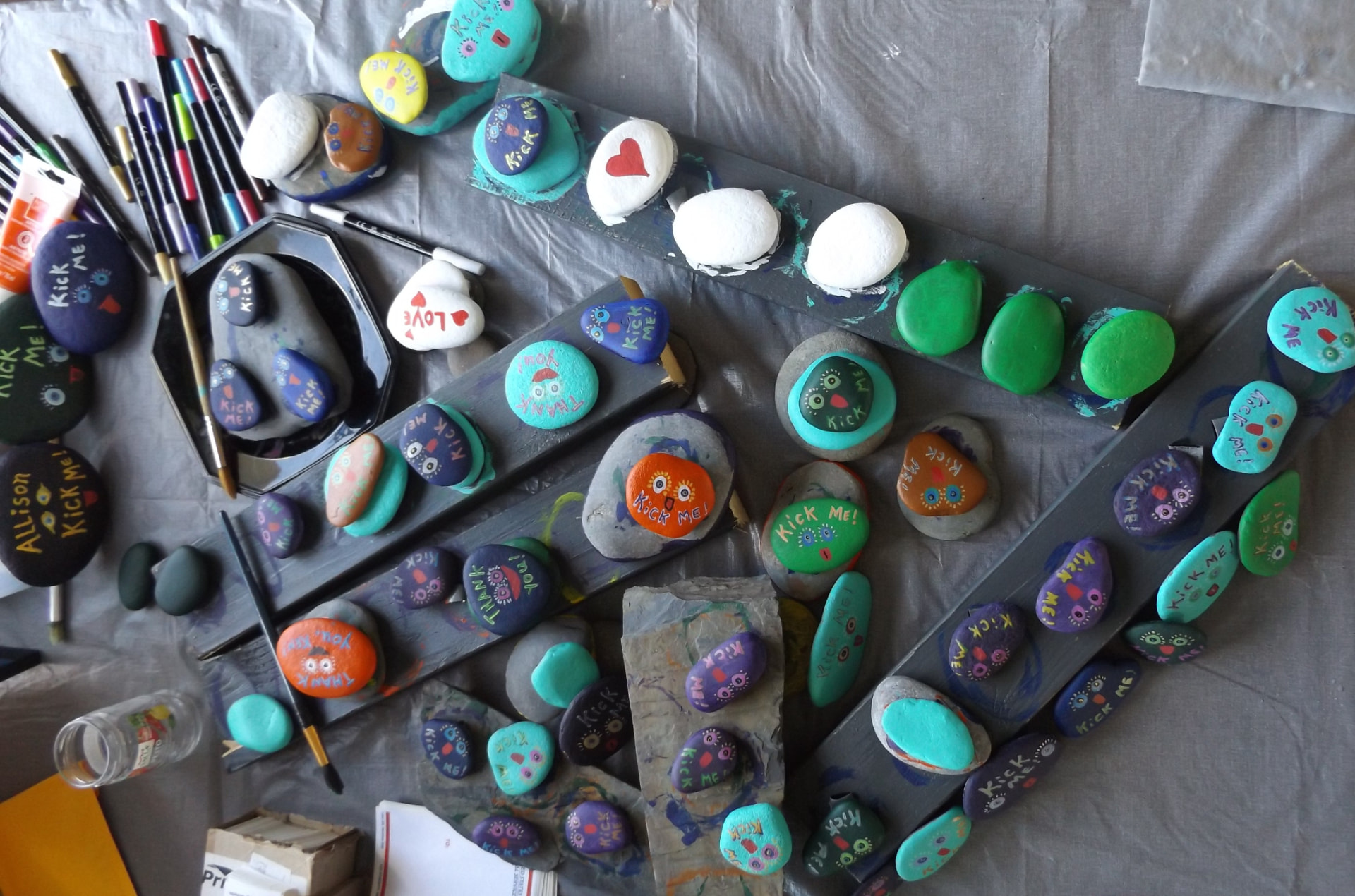 Rows of freshly painted rocks with eyes drying on the work table