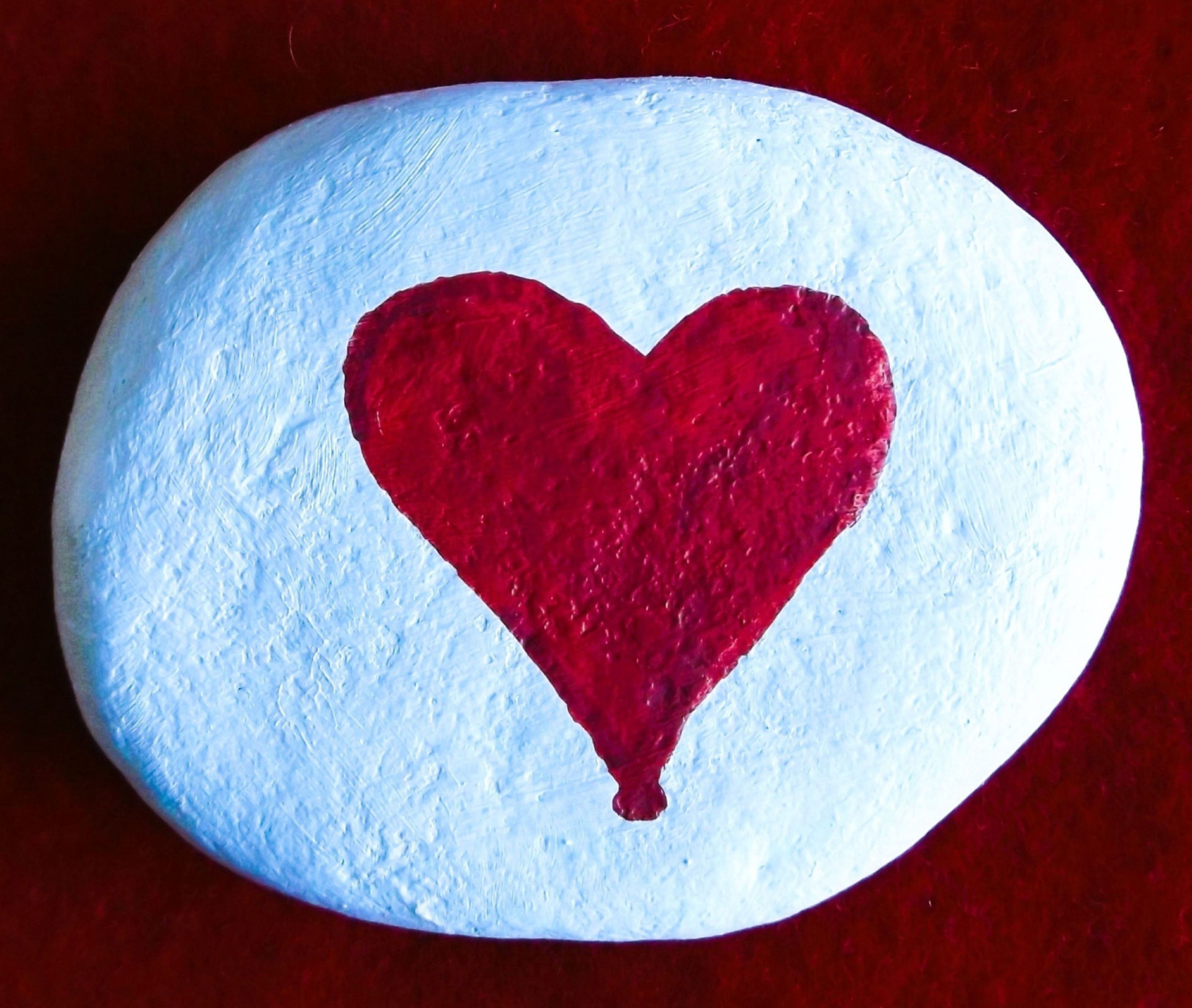 White hand-painted rock with a large red heart