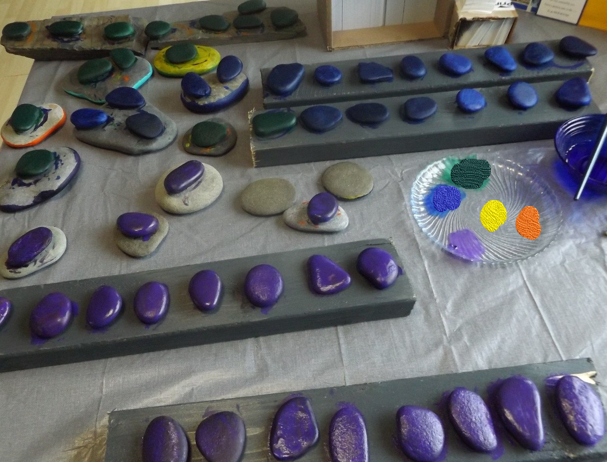 Rows of freshly painted purple and blue rocks drying on boards