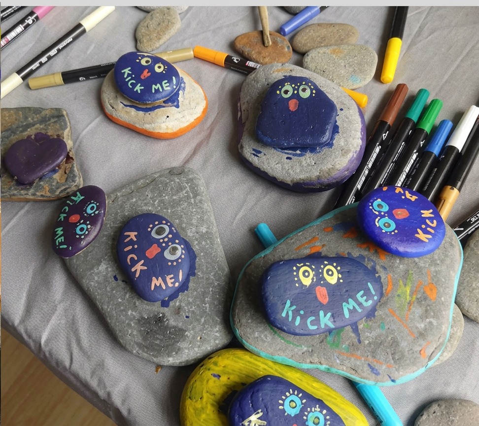 Painted rocks beside a jar of paint brushes